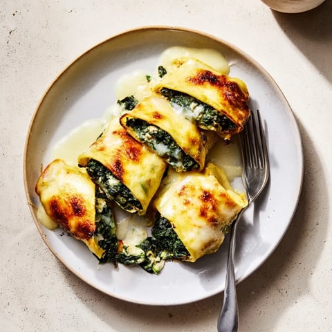 Zart gefüllte Pfannkrollen mit Spinat und Käse, goldbraun gebacken für ein vegetarisches Festmahl.  